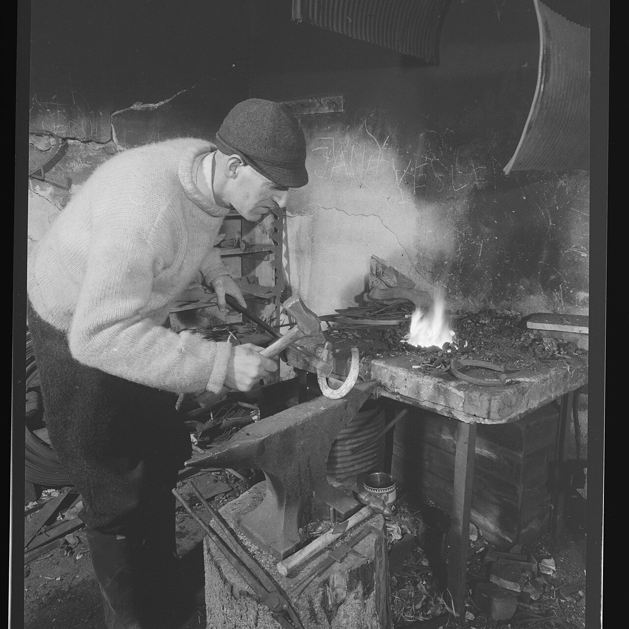 A blacksmith forging a horseshoe at a forge