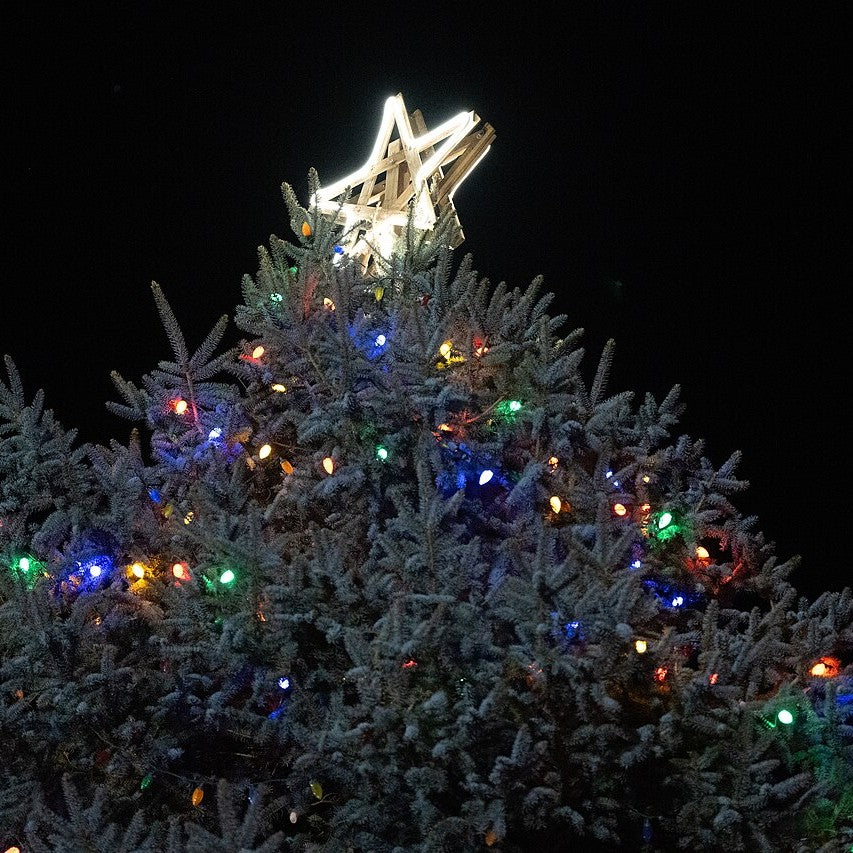 A lit star topper on a snowy Christmas tree