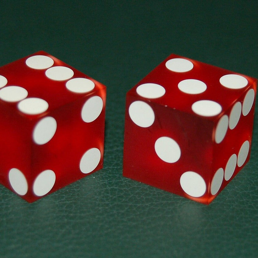 Two red casino dice on a green felt table