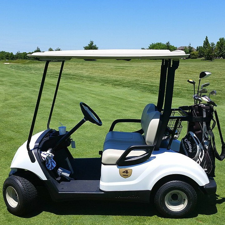 A golf cart on a fairway with clubs