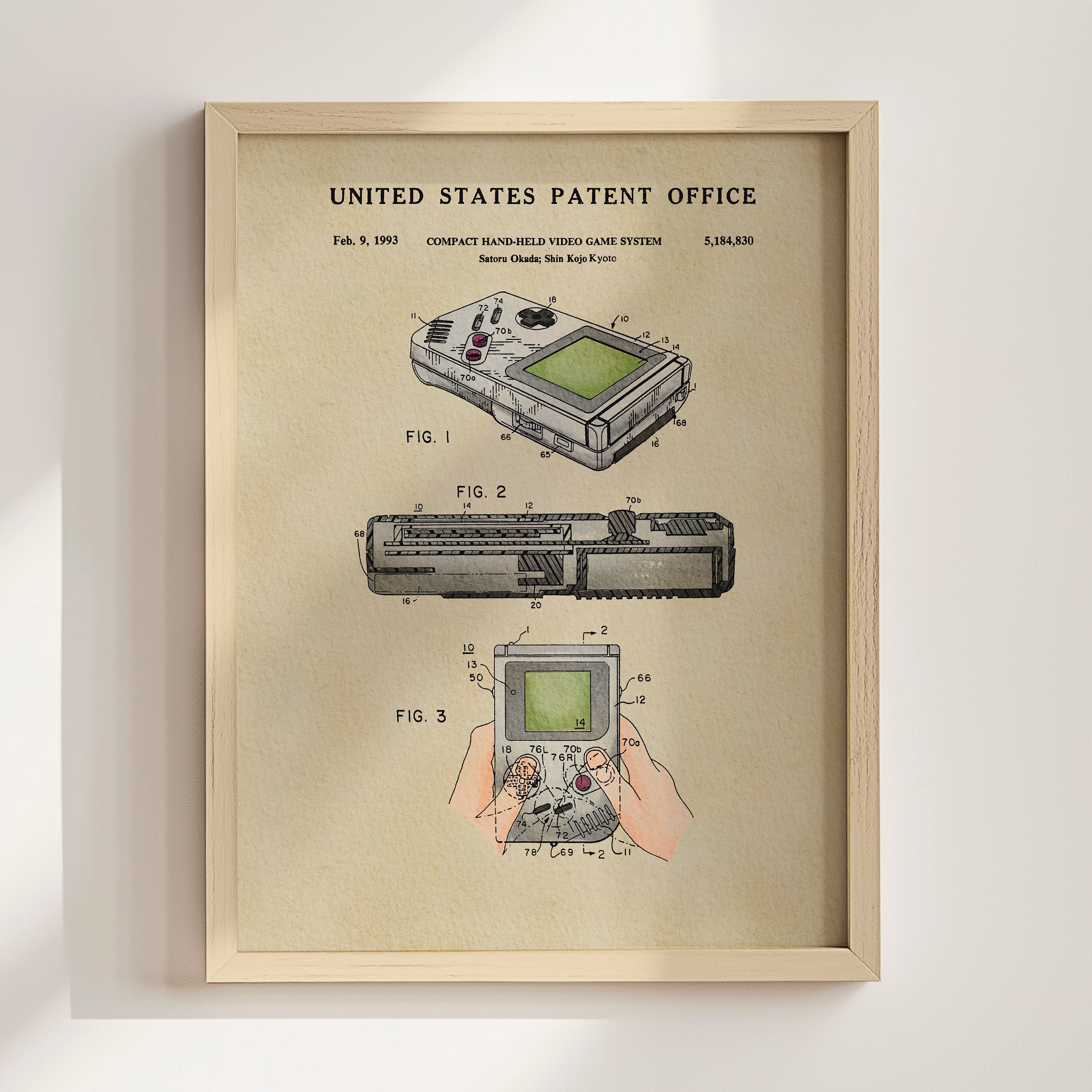 The image is a framed patent drawing depicting a compact handheld video game system, specifically the Nintendo Game System, with three different views of the device.