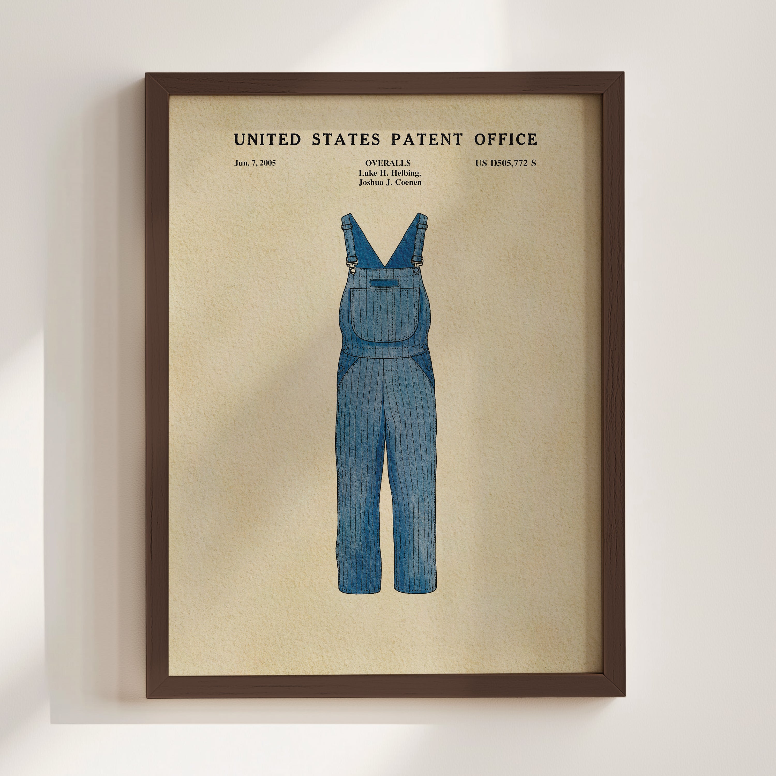The image is a framed print of a blue pair of overalls, depicting a design that resembles a patent invention.