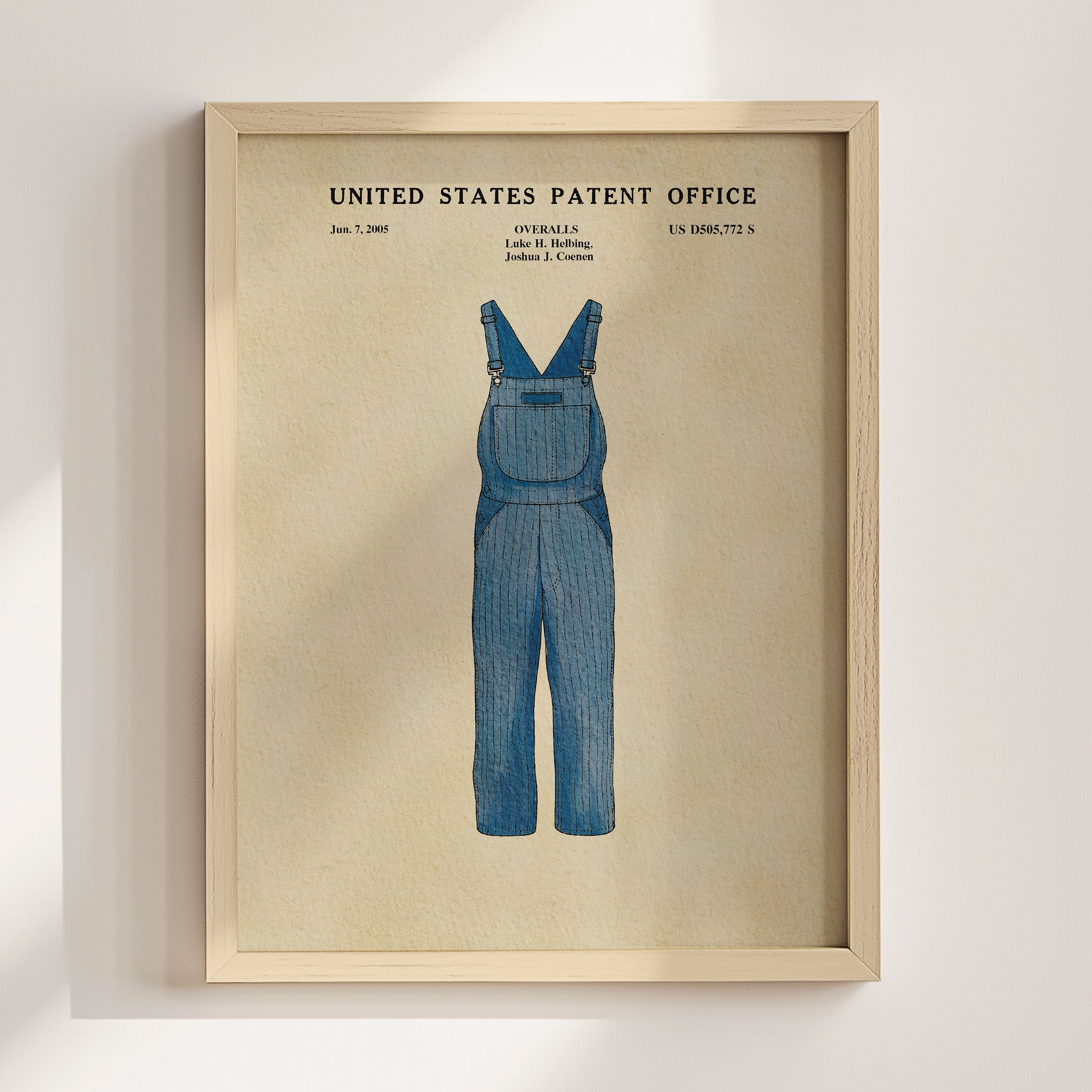 A framed illustration of a pair of blue overalls, depicting a design from the United States Patent Office.