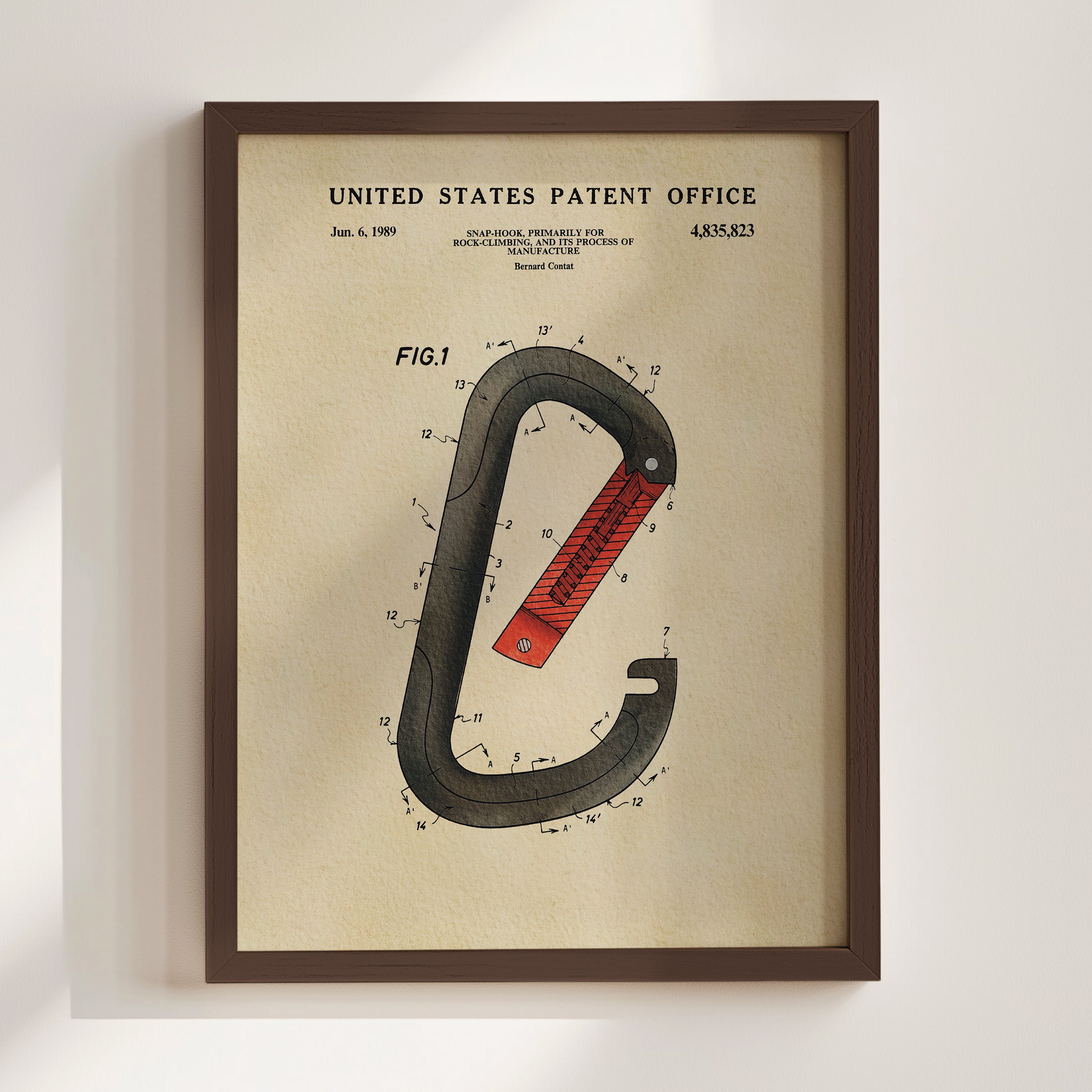 The image is a framed patent drawing depicting a red and black carabiner, a type of hook used for securing items to carabiners.