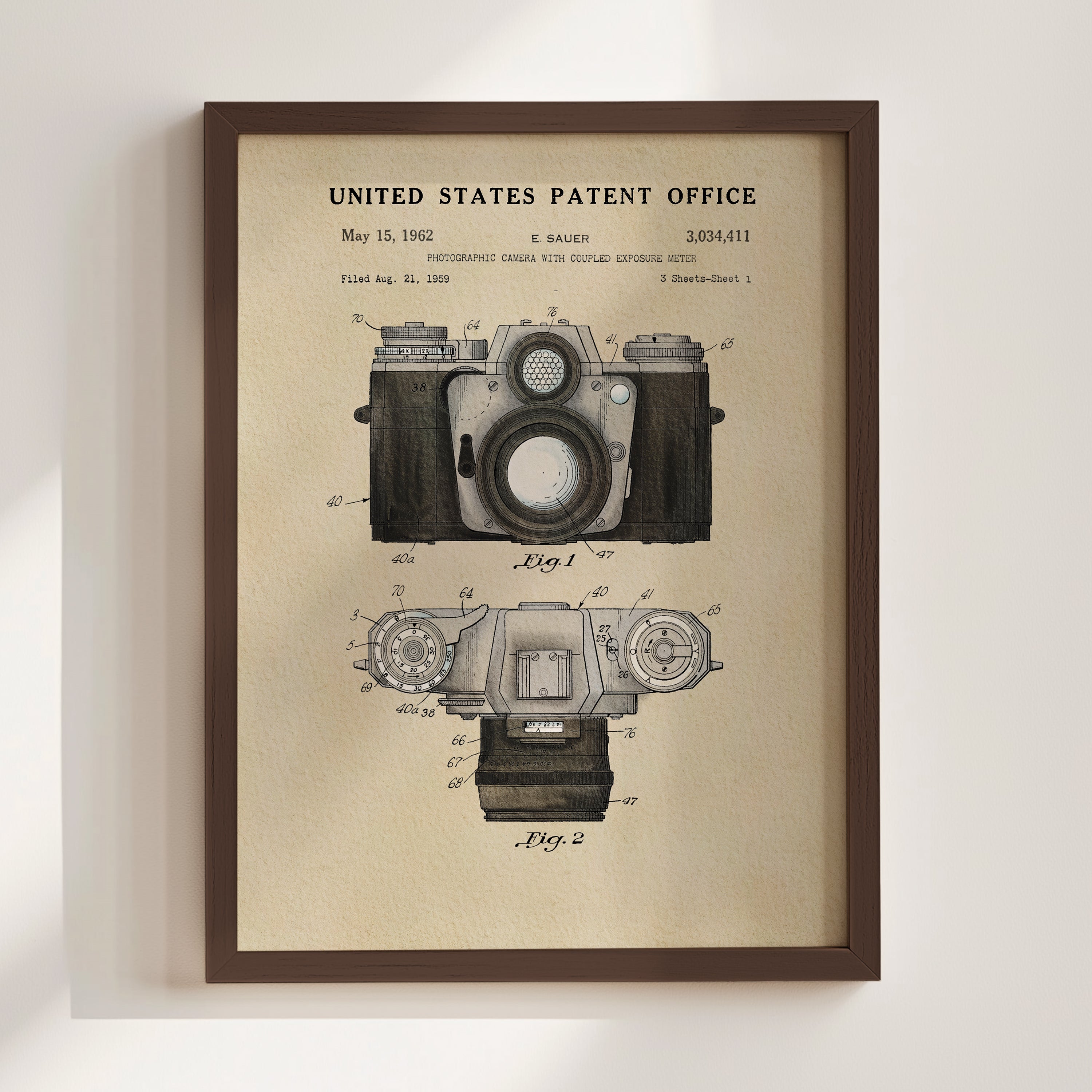 The image is a framed vintage photograph depicting a camera with a technical drawing of its components.