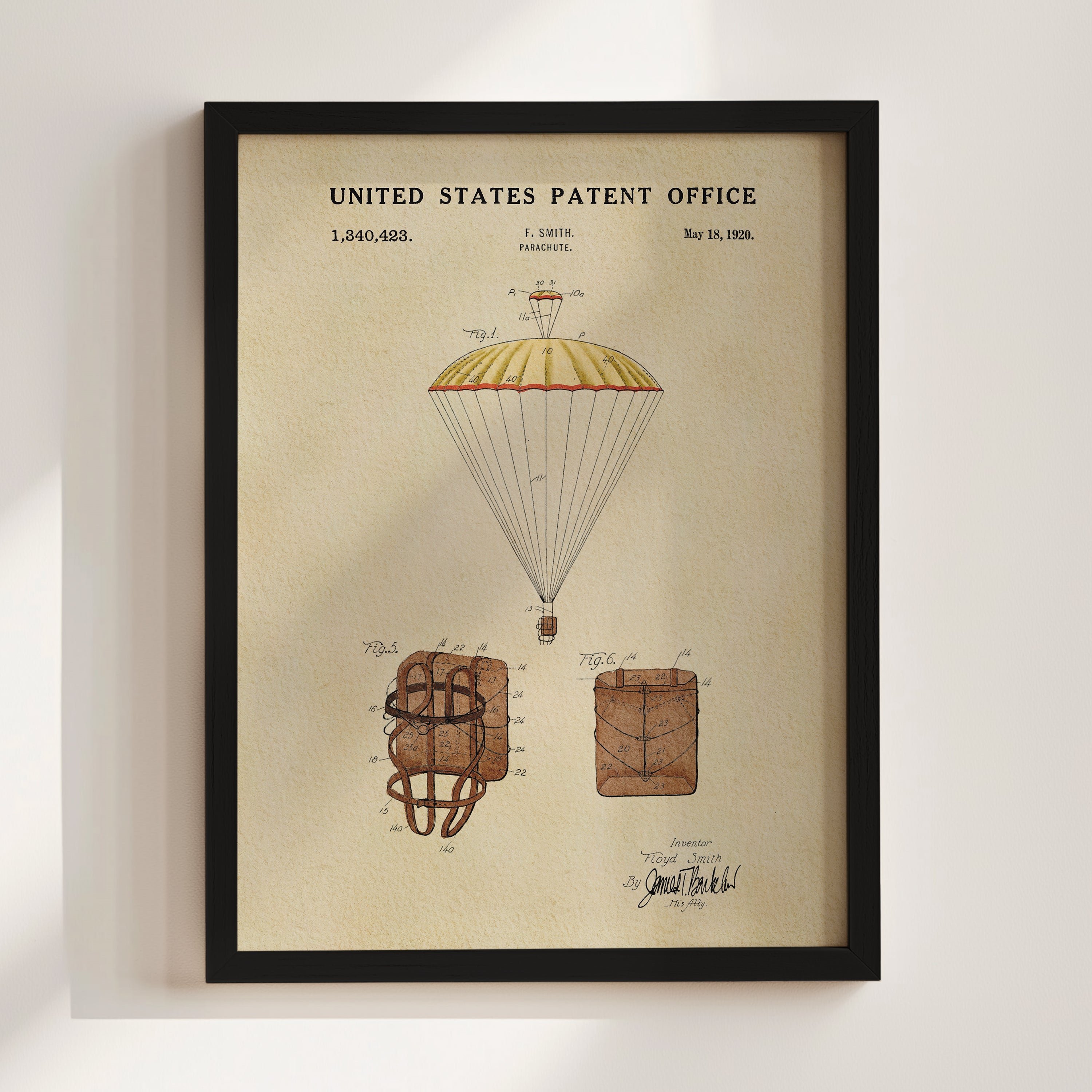 The image is a framed patent drawing depicting a parachute with a yellow and red canopy, along with two smaller parachute designs.