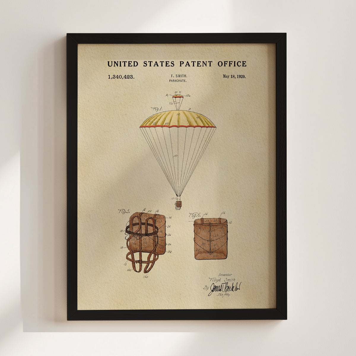 The image is a framed patent drawing depicting a parachute with a yellow and red canopy, along with two smaller parachute designs.