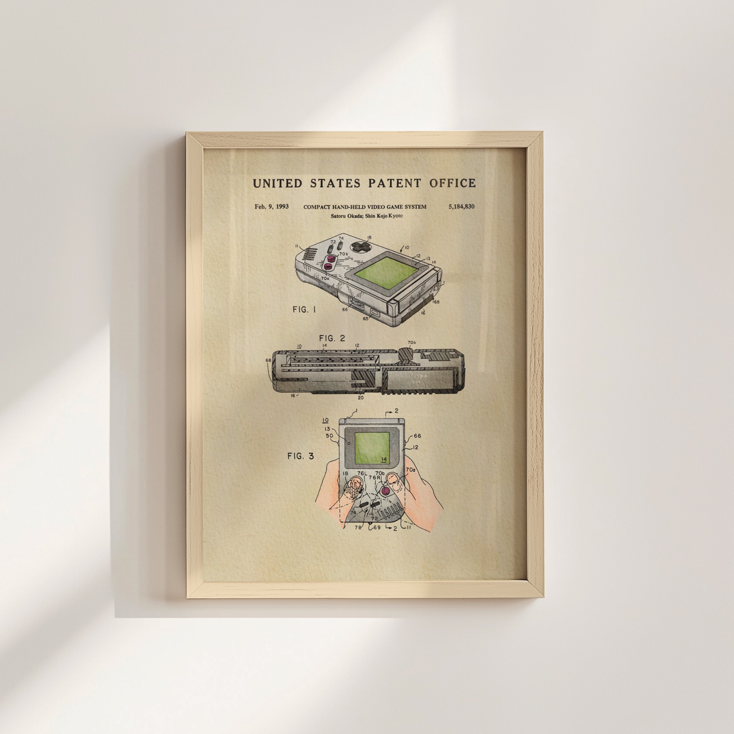 The image is a framed print of a United States Patent Office patent for a compact handheld video game system, specifically the Gameboy Advance.