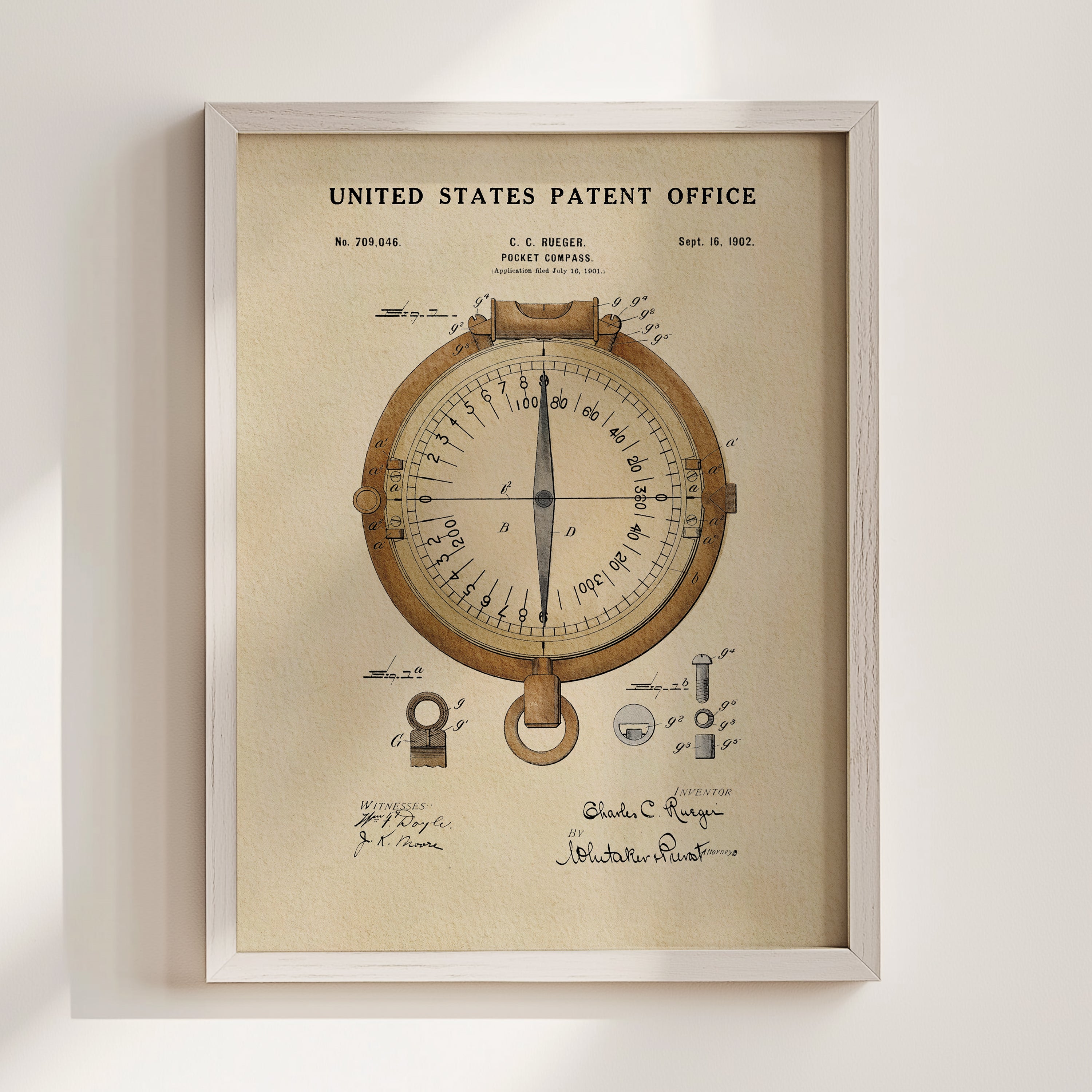 The image is a framed patent drawing depicting a compass, with various technical drawings and annotations surrounding the compass.