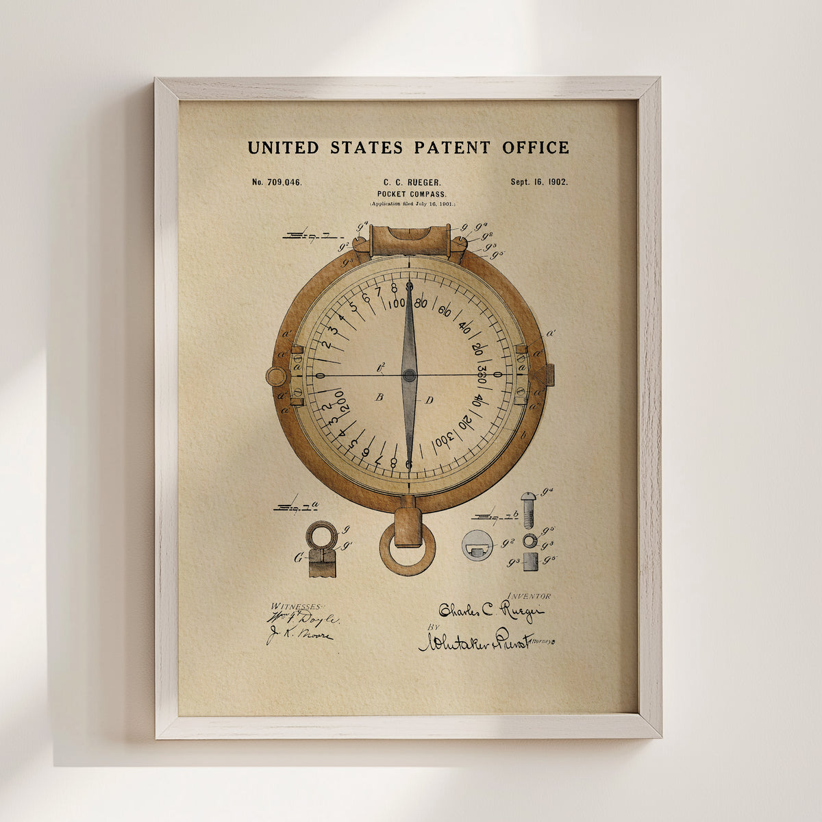 The image is a framed patent drawing depicting a compass, with various technical drawings and annotations surrounding the compass.